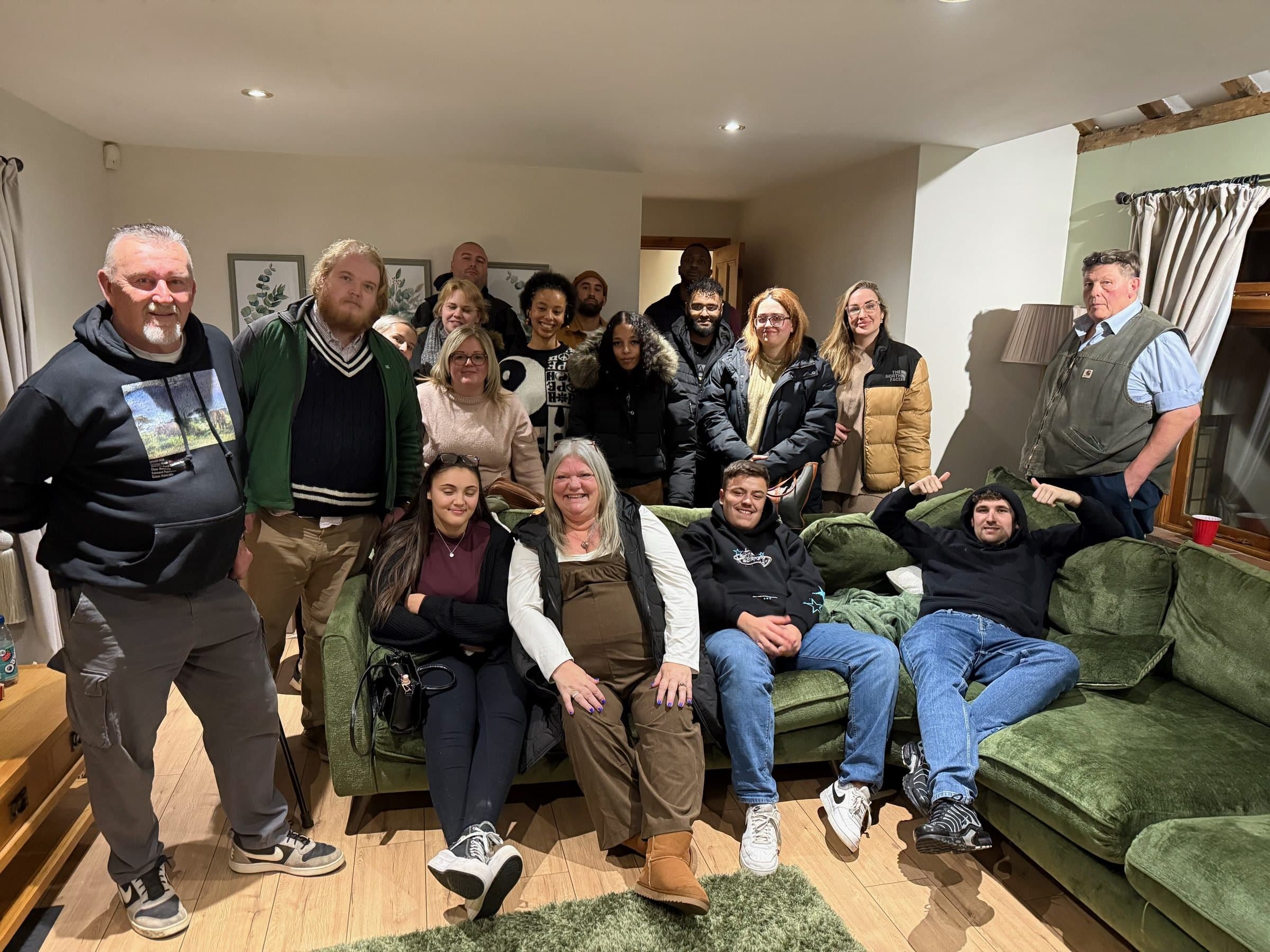 A group of LENs Experts by Experience and staff together in a lounge, smiling at the camera.
